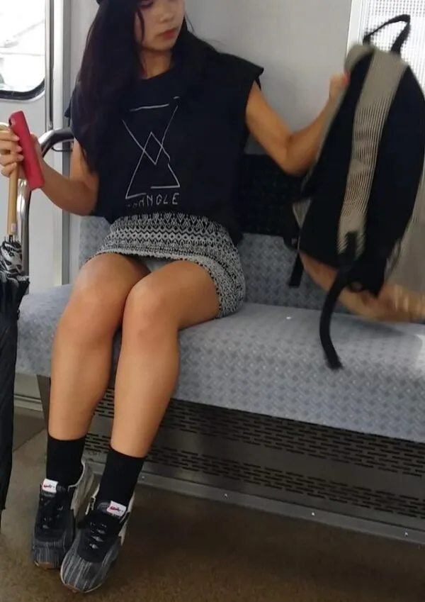 電車内で座る女が白黒模様のミニスカートを履き、膝を閉じて座る姿から見えるドスケベな股間と、スカート奥に覗く薄ピンク色のパンティが淫らに映えるエロ画像。
