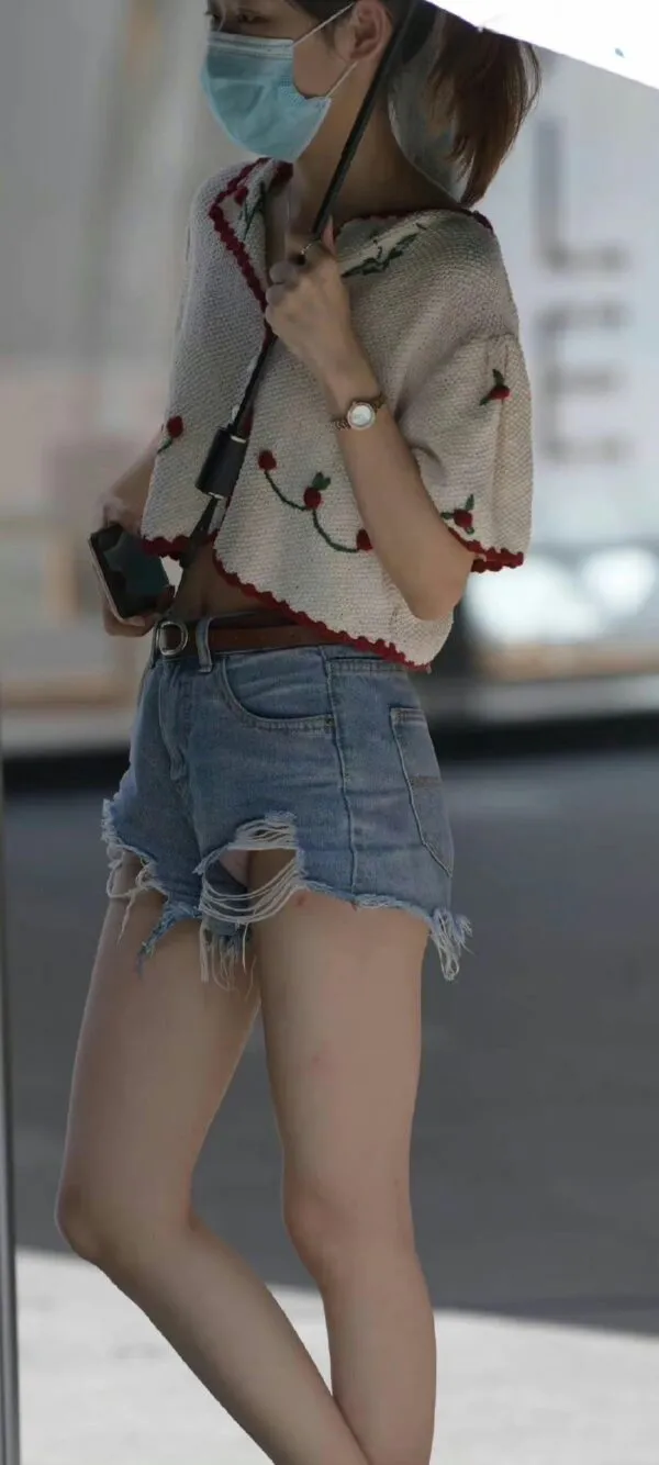 デニムのショートパンツの股間から白いパンティがパンチラしてるのに気づいてない女の写真2
