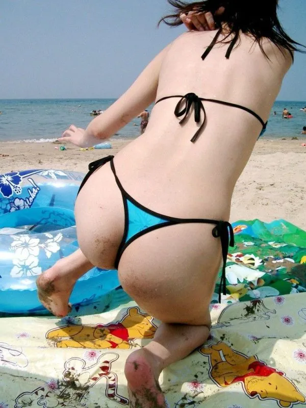 砂浜でレジャーシートの上でしゃがんでTバックビキニからハミ出たムチムチの生尻を見せてる素人ギャルを撮影した写真