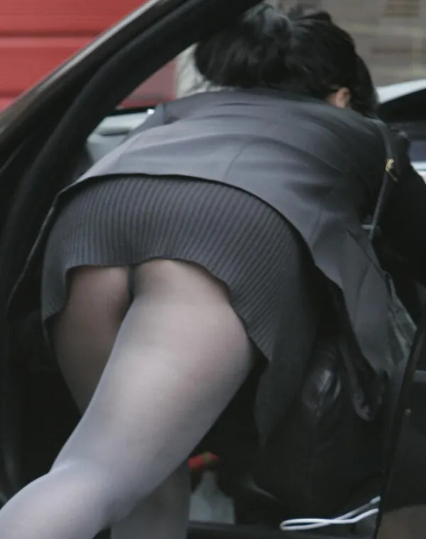 黒パンストを履いた女が車の中に身を乗り出し、短いグレーのスカートからムチムチ尻が卑猥に見えるエロ画像