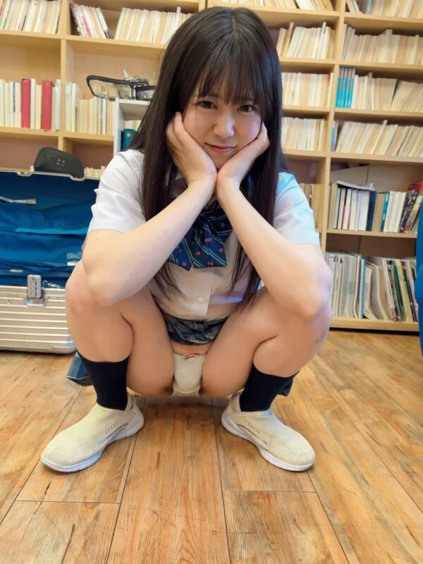 JKが制服の青色チェック柄スカートをめくり、床にしゃがみ込みながら白色のパンツの股間を淫らに見せているエロ画像