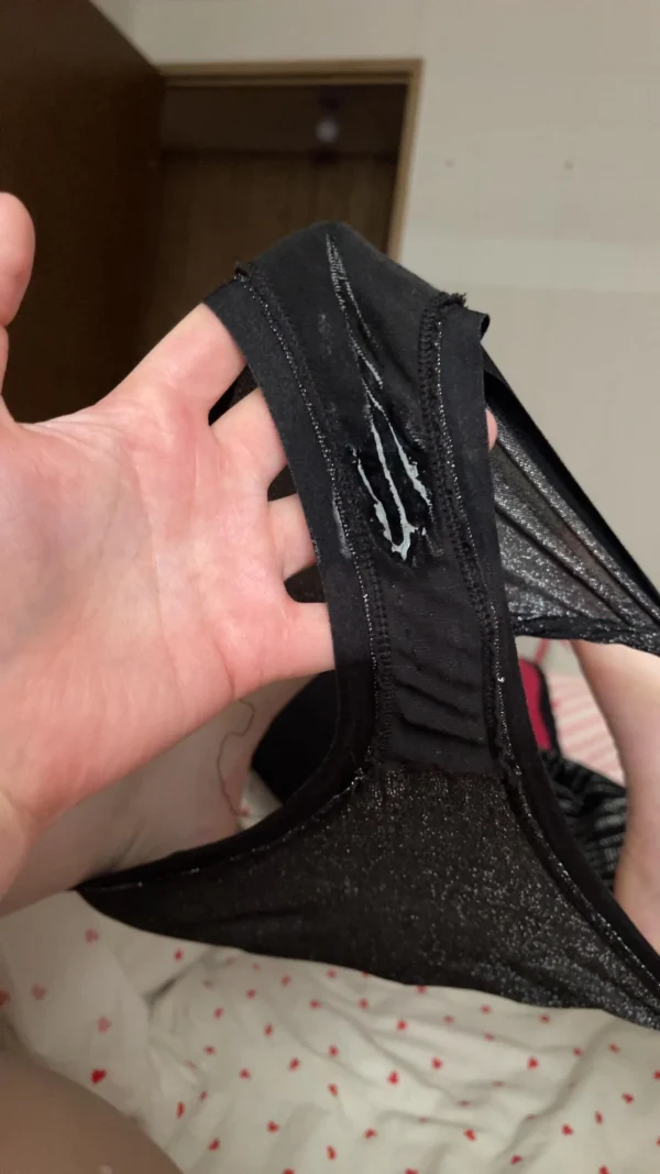 黒いパンティを手に持ち、股間に白濁したマン汁が濃厚にべっとり付着している様子を捉えた一枚。