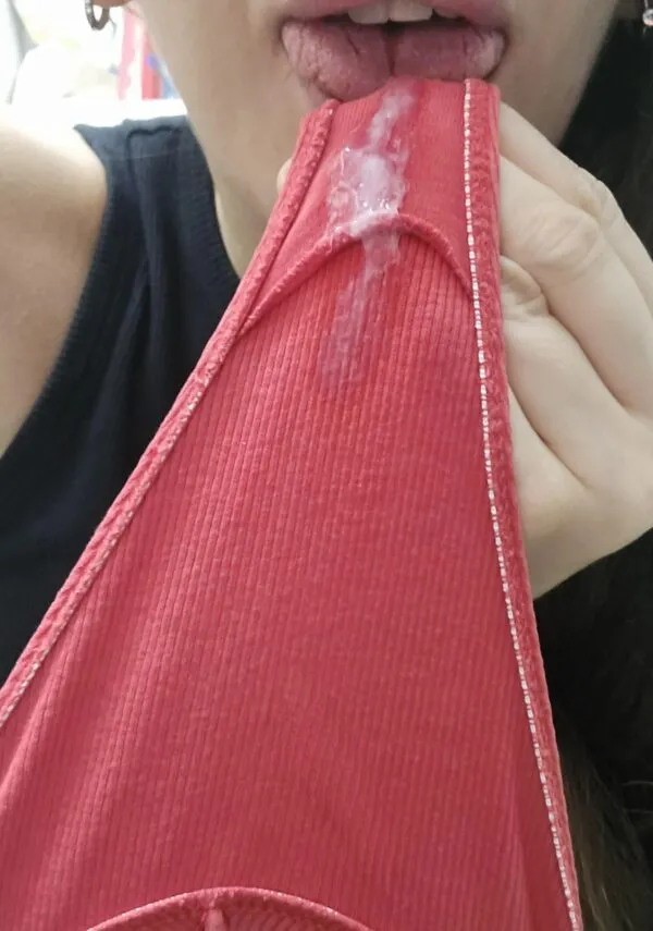 黒いトップスを着た女が赤いパンティの股間部分を舌で舐めており、パンティにはマン汁がべっとり付着している様子が映し出されている。