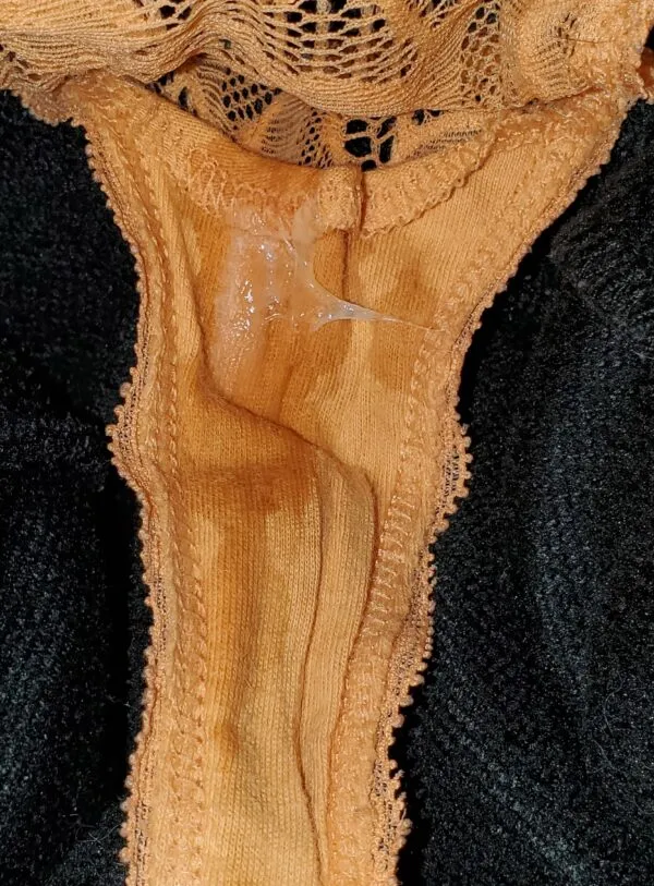 黒い服を着た女の股間にオレンジ色のパンティが食い込み、マン汁がべっとりと染みついた様子が濃厚に映し出されている。