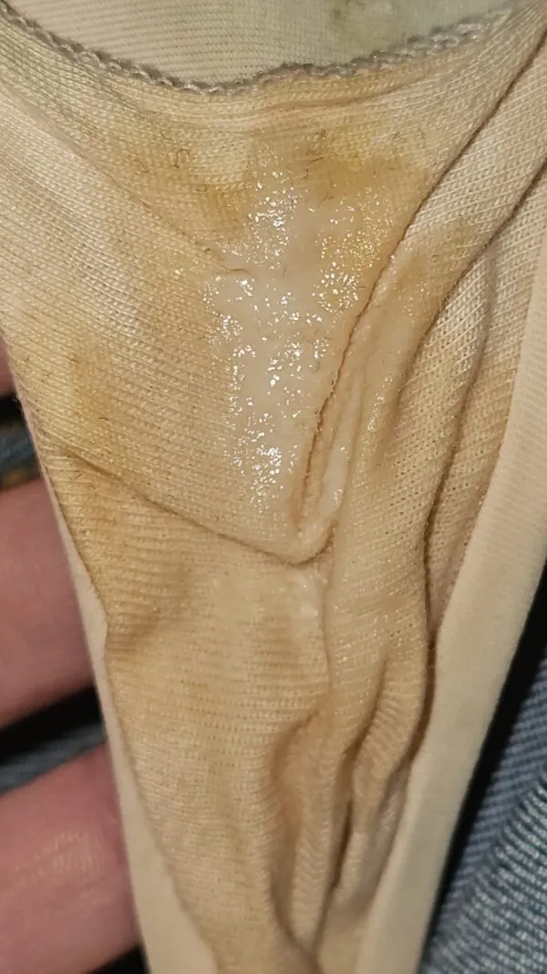 ベージュのパンティの股間部分に濃厚なオリモノがべっとり付着している女の股間のアップ画像。