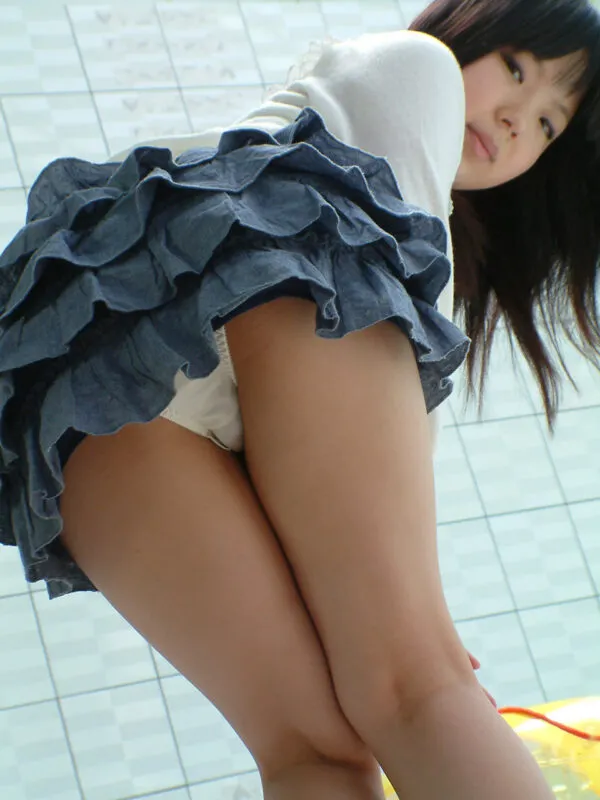 優雅な青いフリルスカートの下から白いパンティ尻を撮影した、室内で脚を組みながら見せる女の淫らな尻エロ画像