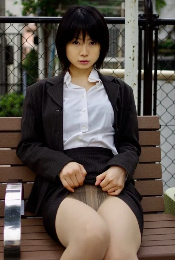 野外のベンチに座る女が黒のスカートをめくり上げ、透け感のあるベージュのパンティを露出させた淫乱な股間を撮影したエロ画像。